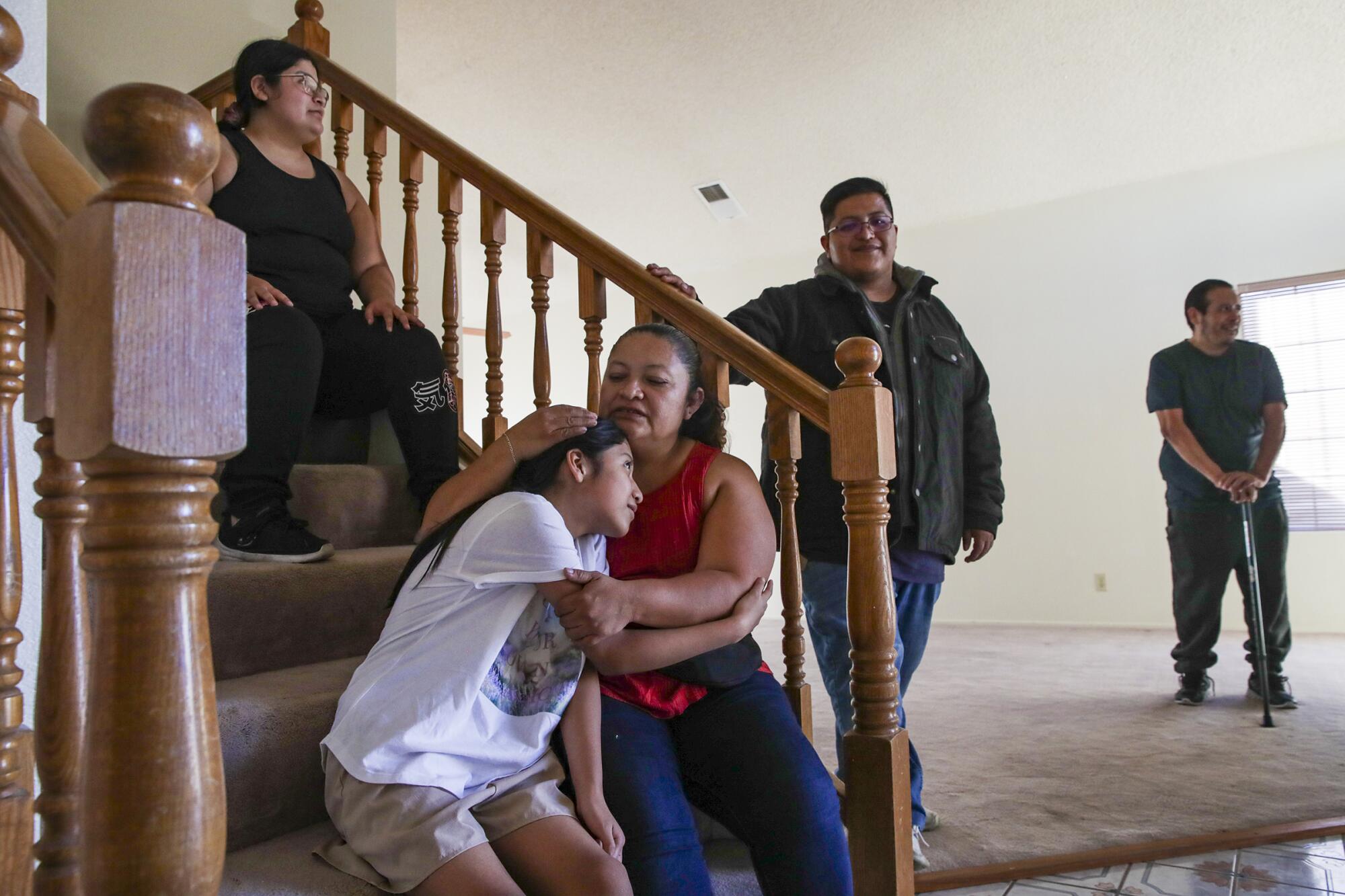 Juana Oceguera hugs her 10-year-old daughter, Xochitl Martinez, as the family relax in their new home in Lancaster.