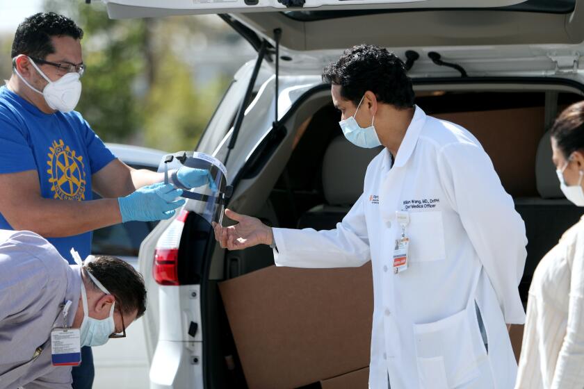 Dignity Health Glendale Memorial Hospital chief medical officer Dr. William Wang, center, looks over face shields delivered by Glendale Sunrise Rotary president Alex Parajon, left, and other members of the club, to the hospital in Glendale on Tuesday, April 14, 2020. Seven-hundred and fifty of 1,000 masks were delivered to the hospital with the balance coming soon. The two other local hospitals in Glendale will also receive 1,000 face shields from the local Sunrise Rotary.