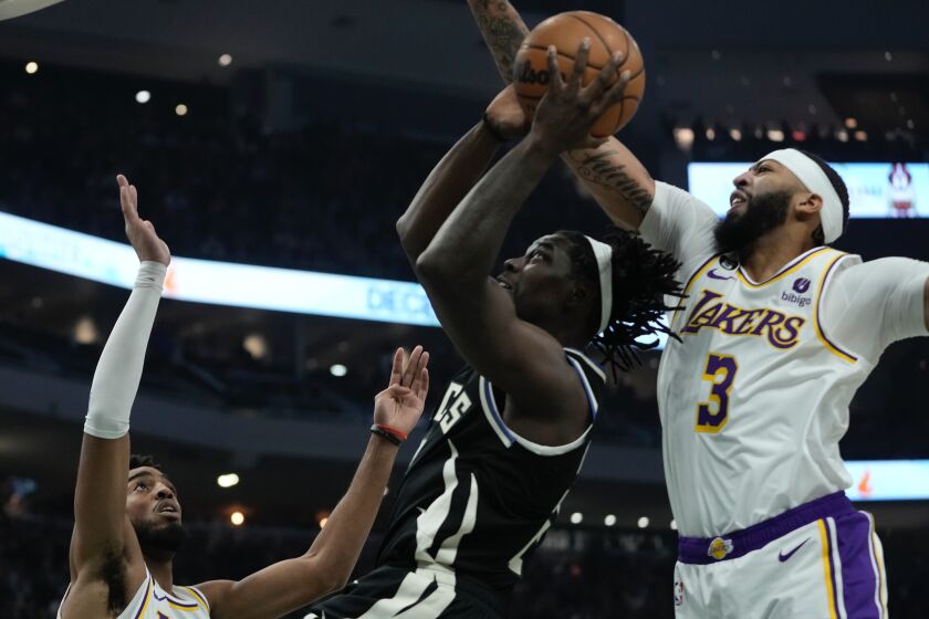 Milwaukee Bucks' Jrue Holiday shoots between Los Angeles Lakers' Troy Brown Jr. and Anthony Davis during the first half of an NBA basketball game Friday, Dec. 2, 2022, in Milwaukee. (AP Photo/Morry Gash)