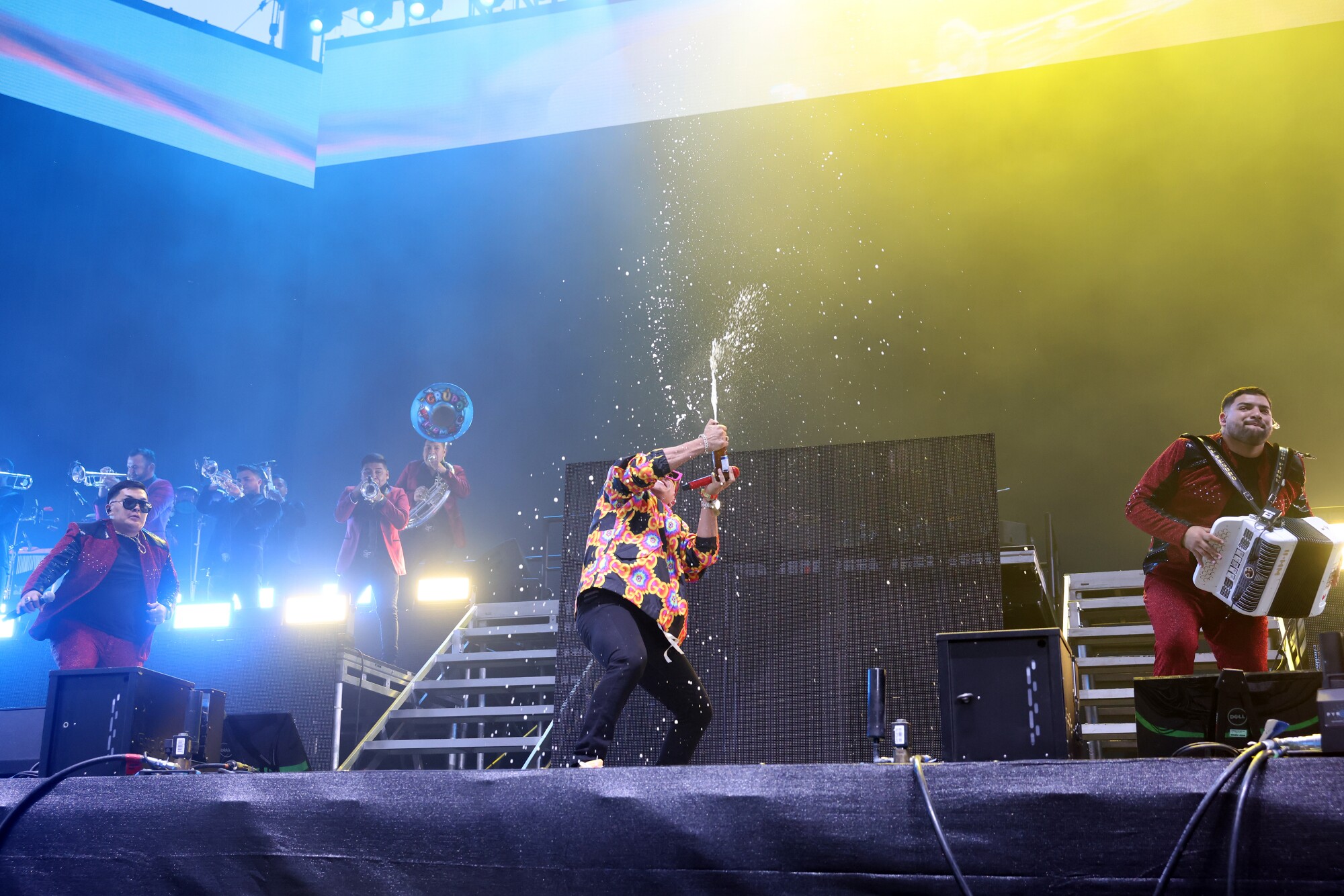 Grupo Firme sprays a drink in the air while performing at the Coachella festival.