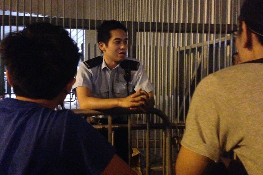 A Hong Kong police officer casually talks to protesters across a metal barricade in the early hours of Oct. 6 outside the offices of Chief Executive Leung Chun-ying.