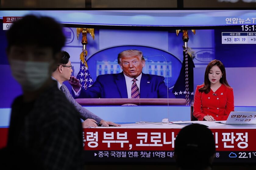 A commuter at the Seoul Railway Station walks past a TV screen featuring coverage about President Trump.