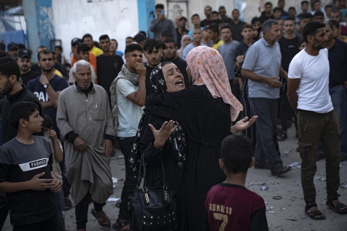 Mujeres llorando mientras se saca a víctimas de entre los escombros