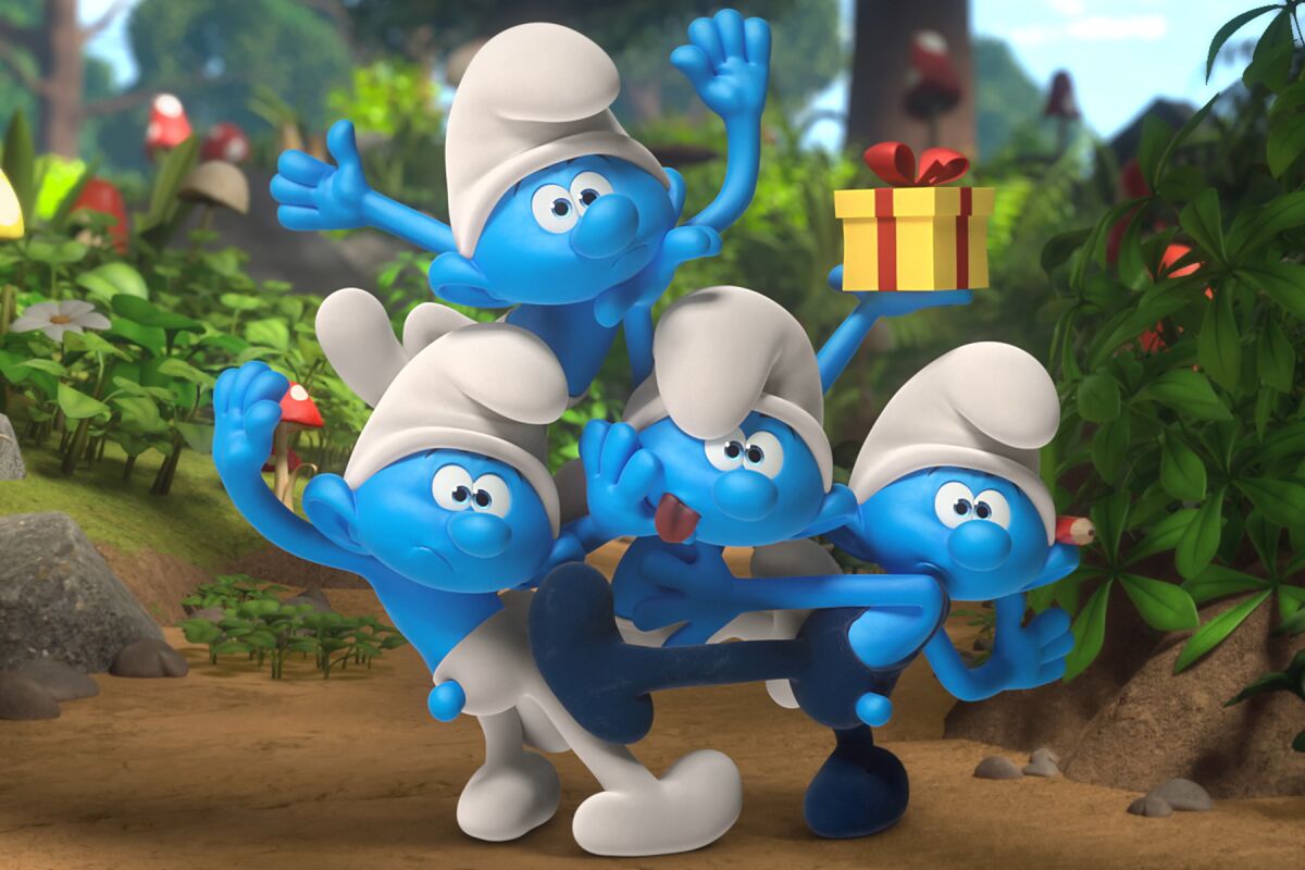 Four Smurfs in a clearing, one holding a wrapped present.