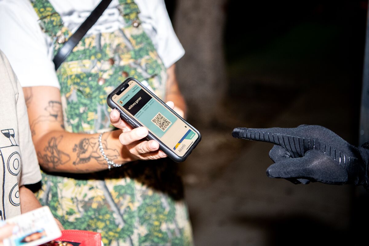 A security officer checks the vaccination record on a patron's smartphone 