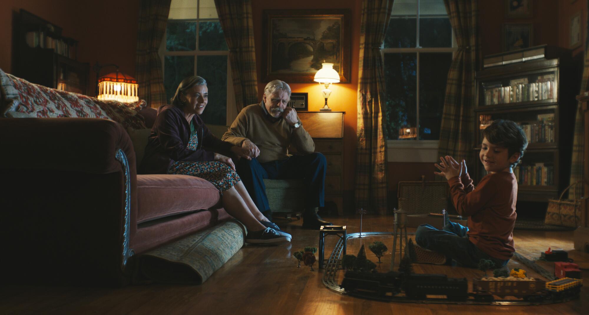 A family plays with a happy boy in a living room.