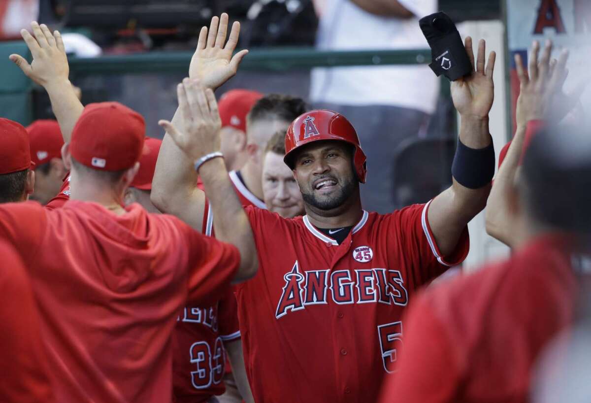 Albert Pujols (c) recibe la felicitación de sus compañeros en la banca tras anotar, en la reciente victoria de los Angels en Anaheim, California.