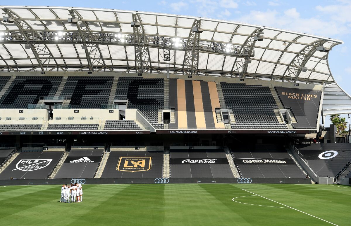 Galaxy soccer players gather at an empty stadium before a game against LAFC at Banc of California 