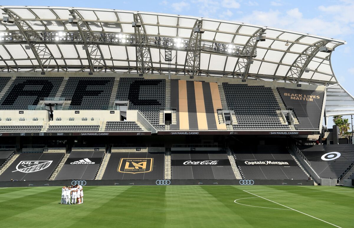 Galaxy soccer players gather at an empty stadium before a game against LAFC at Banc of California