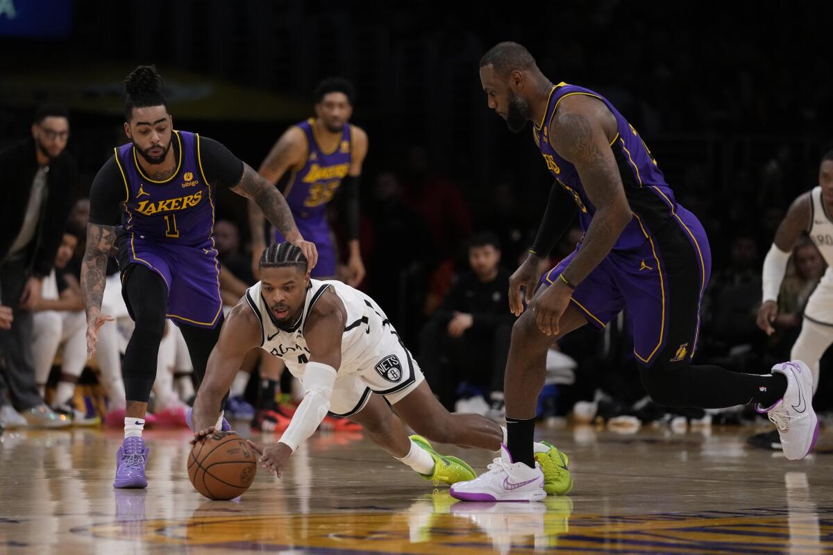 Brooklyn Nets guard Dennis Smith Jr. dives for a loose ball in front of Lakers' D'Angelo Russell and LeBron James.