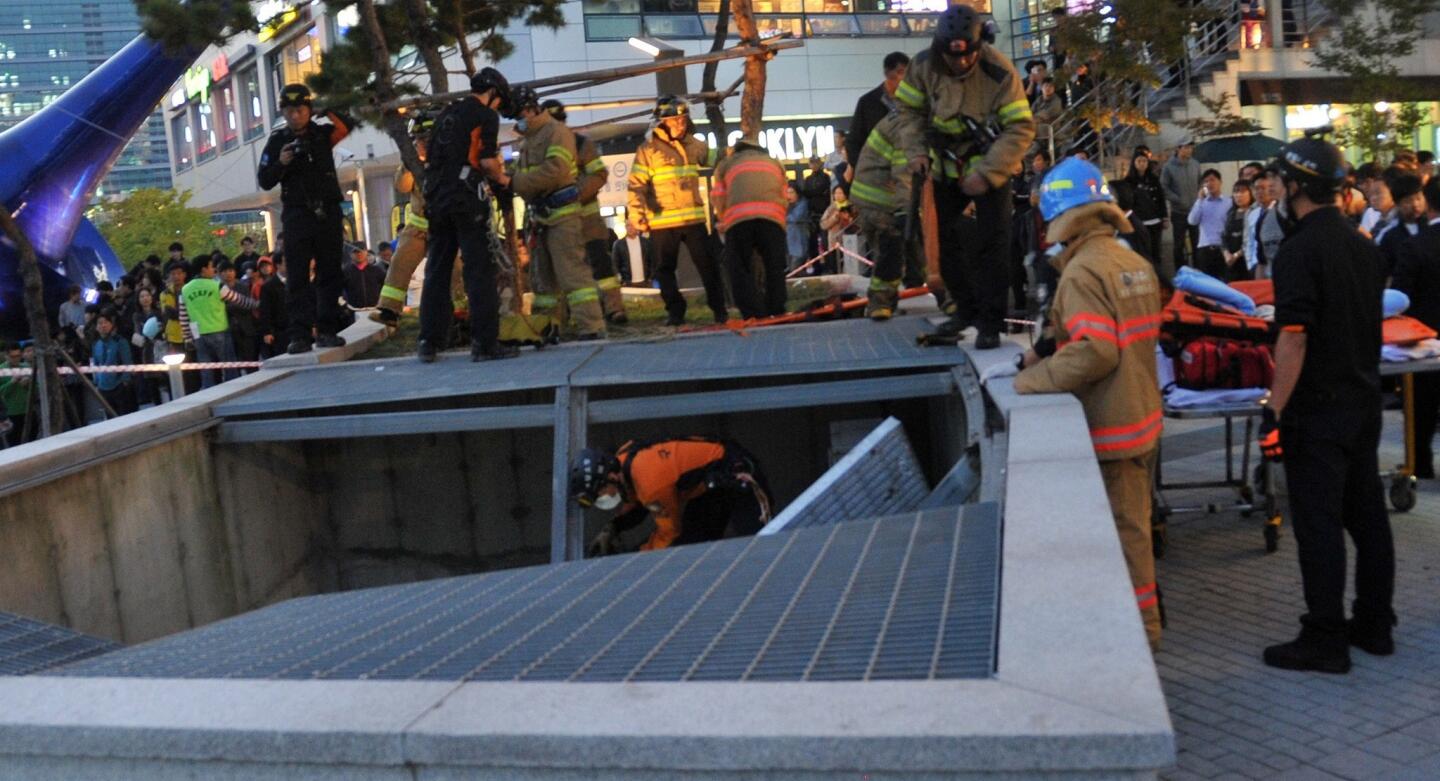 Rescue crews check the ventilation grate that collapsed beneath concert goers in Seongnam.