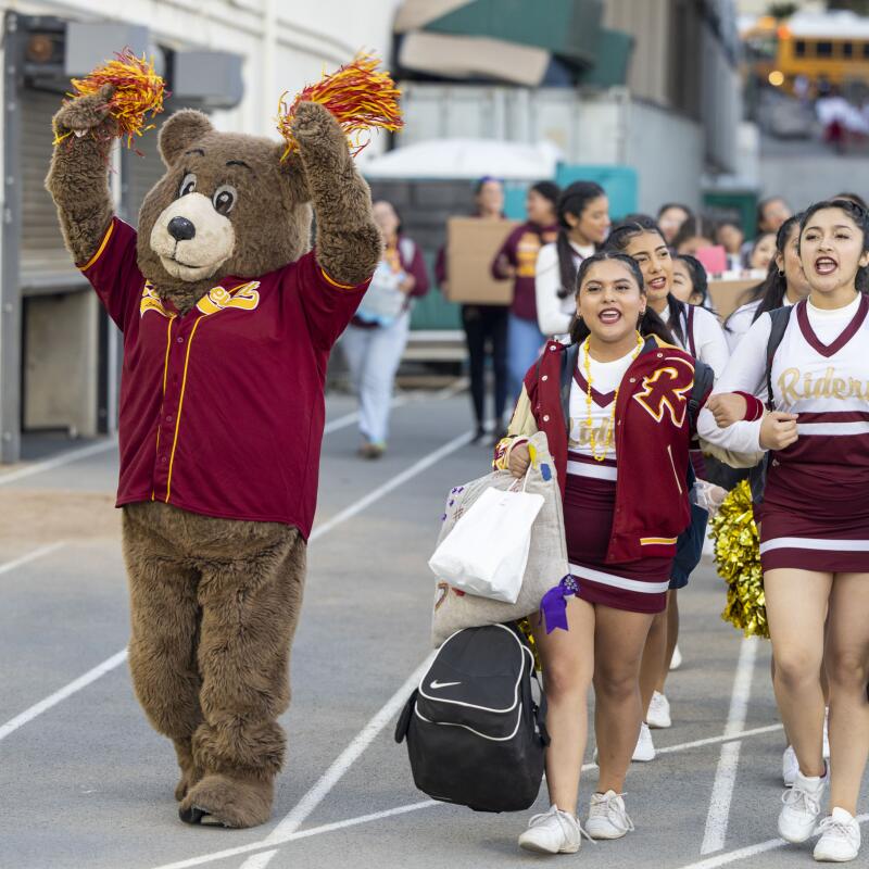 The Roosevelt High cheerleaders and the team mascot mascot arrive at Weingart Stadium.