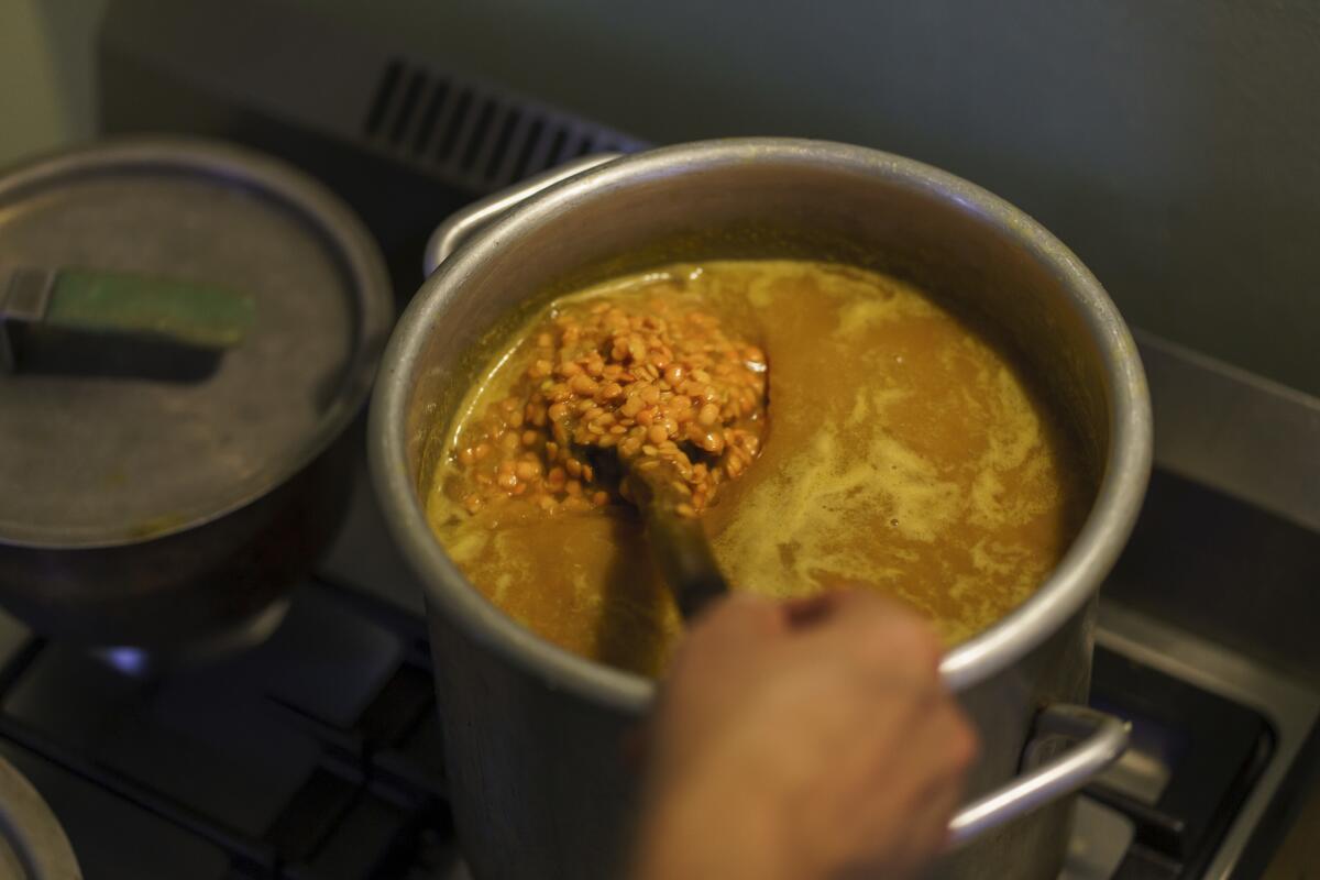 Cal Peternell stirs the pot as he makes dal, an Indian soup made from lentils, to feed the homeless, in Berkeley, Calif., on Dec. 21, 2018. (Marcus Yam / Los Angeles Times)