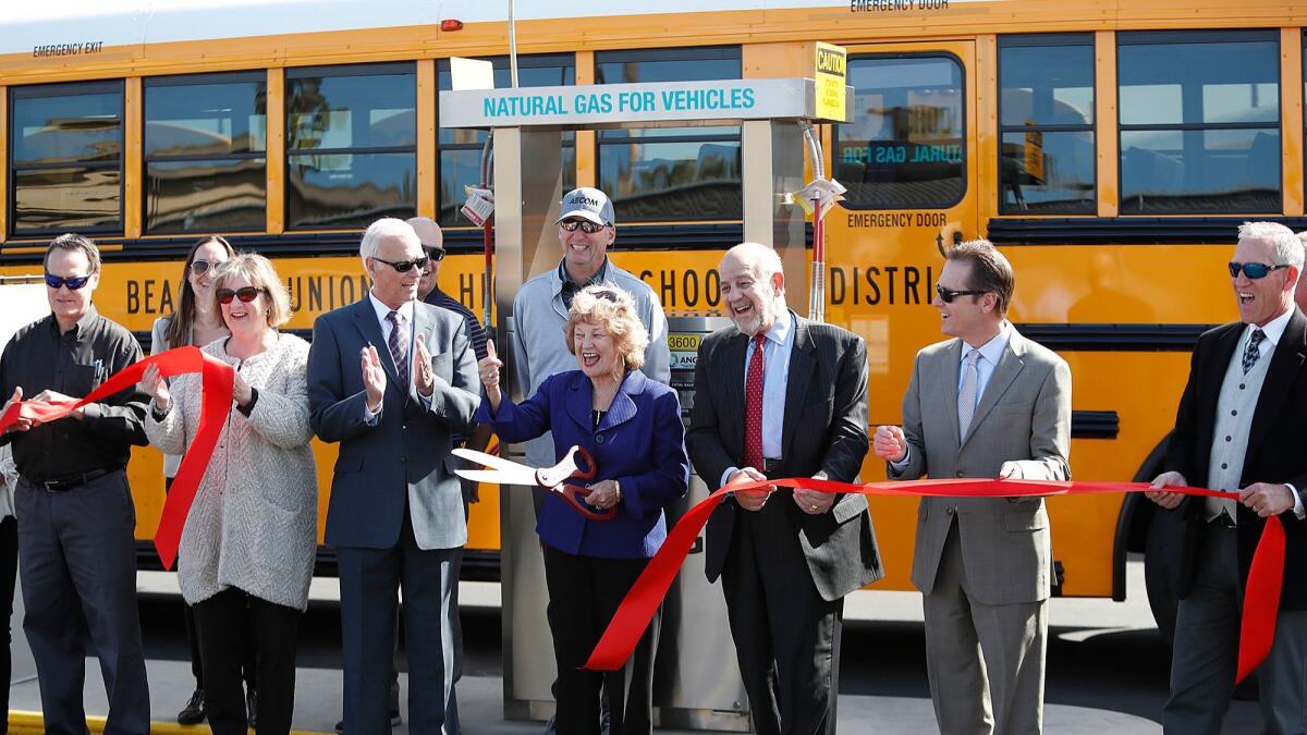 Huntington Beach Union High School District board President Bonnie Castrey cuts a ribbon during a ceremony for the district’s new compressed natural gas station Monday.