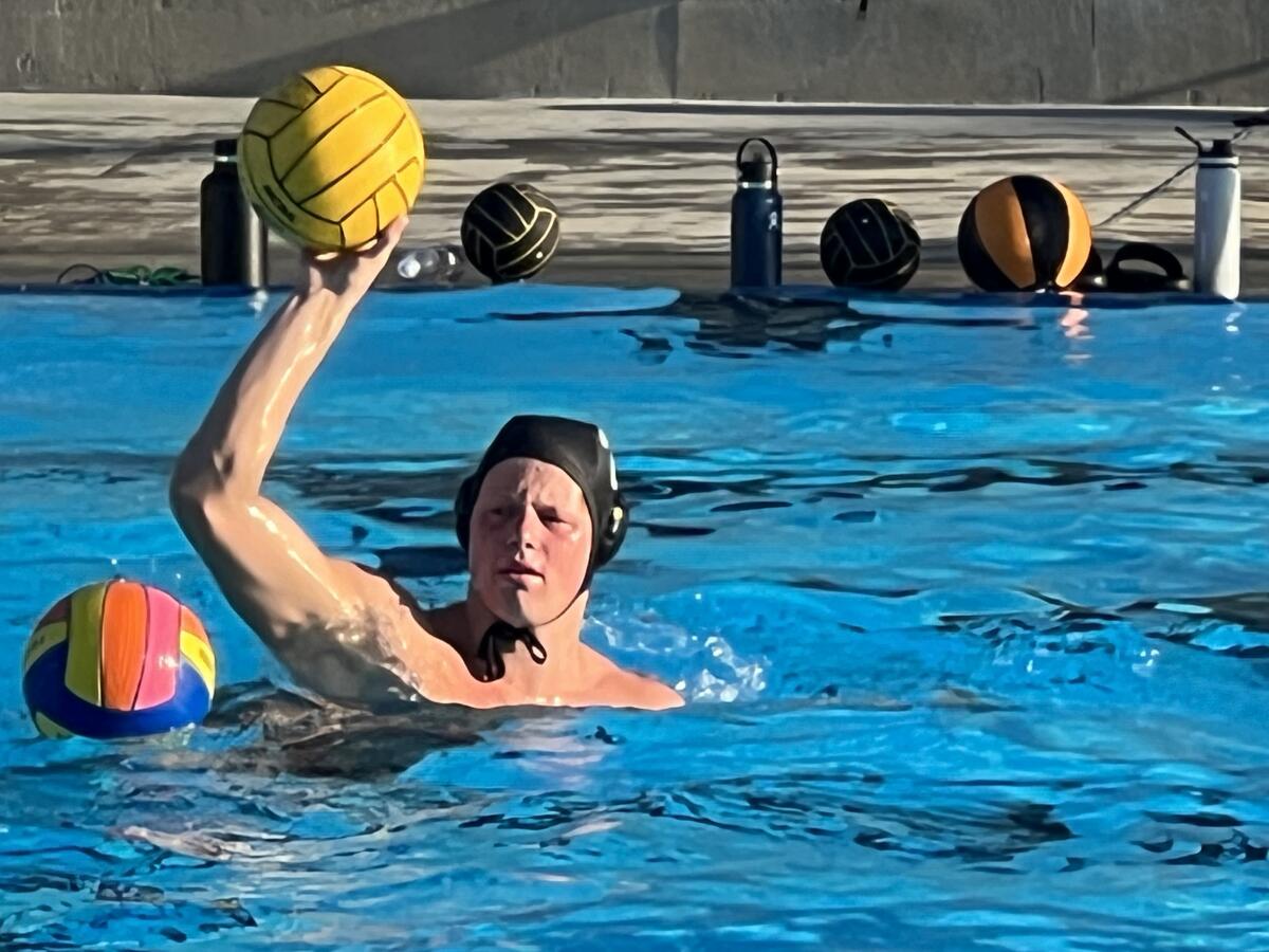 JSerra High's Ryder Dodd holds the water polo ball overhead as he treads water.