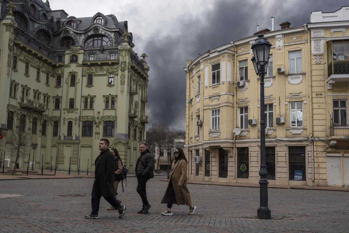 People walk in a street as smoke rises in the air after shelling in Odesa, Ukraine