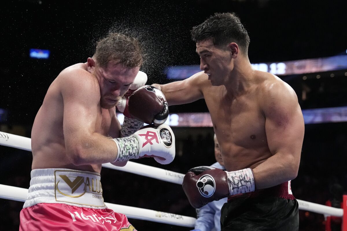 Dmitry Bivol, right, of Kyrgyzstan, throws a punch against Canelo Álvarez.