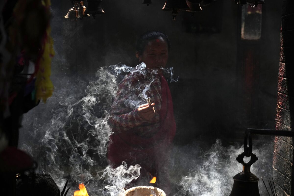 A woman lights incense while she offers prayers during Holi festival in Bhaktapur, Nepal, Thursday, March 17, 2022. The festival marks the advent of spring. (AP Photo/Niranjan Shrestha)