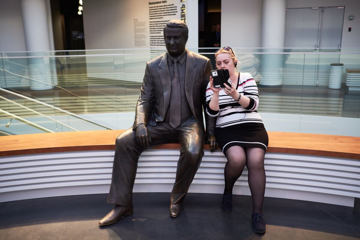 A museum visitor takes a selfie with a bronze statue of Boris Yeltsin inside the Boris Yeltsin Museum.
