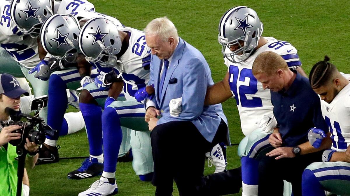 The Dallas Cowboys, led by owner Jerry Jones, center, take a knee prior to the national anthem.