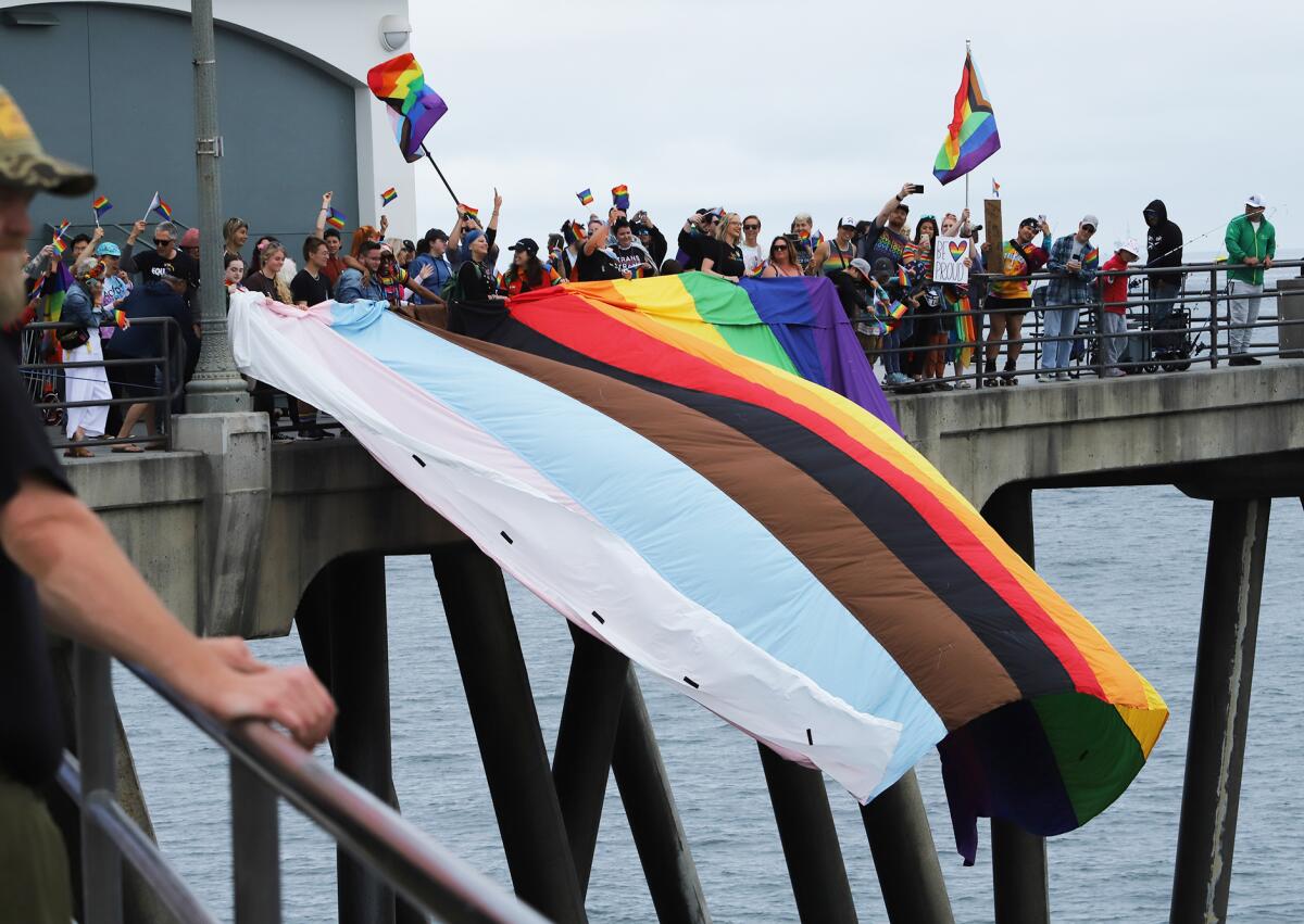 A Pride flag measuring 33 feet by 24 feet is lowered from Huntington Beach pier.
