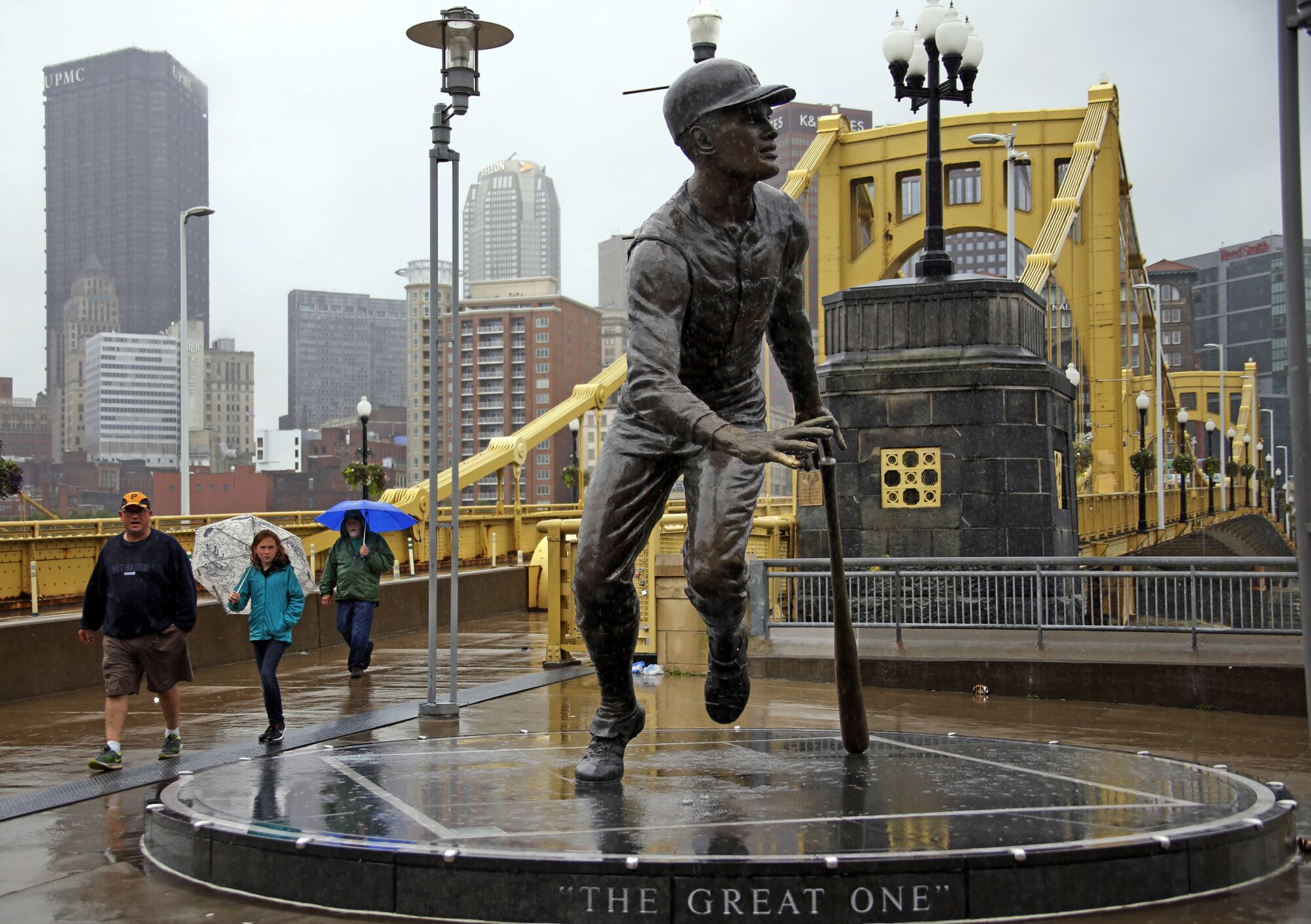 Pirates fans walk past a statue of Roberto Clemente at the end of his namesake bridge outside Pittsburgh's PNC Park