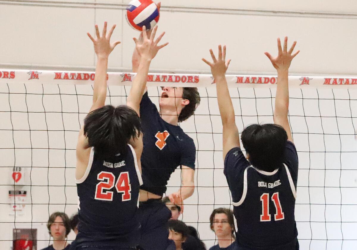 Pacifica Christian's Hudson Reynolds (4) spikes the ball against Bolsa Grande's Peter Pham (24) and Kenny Nguyen (11).