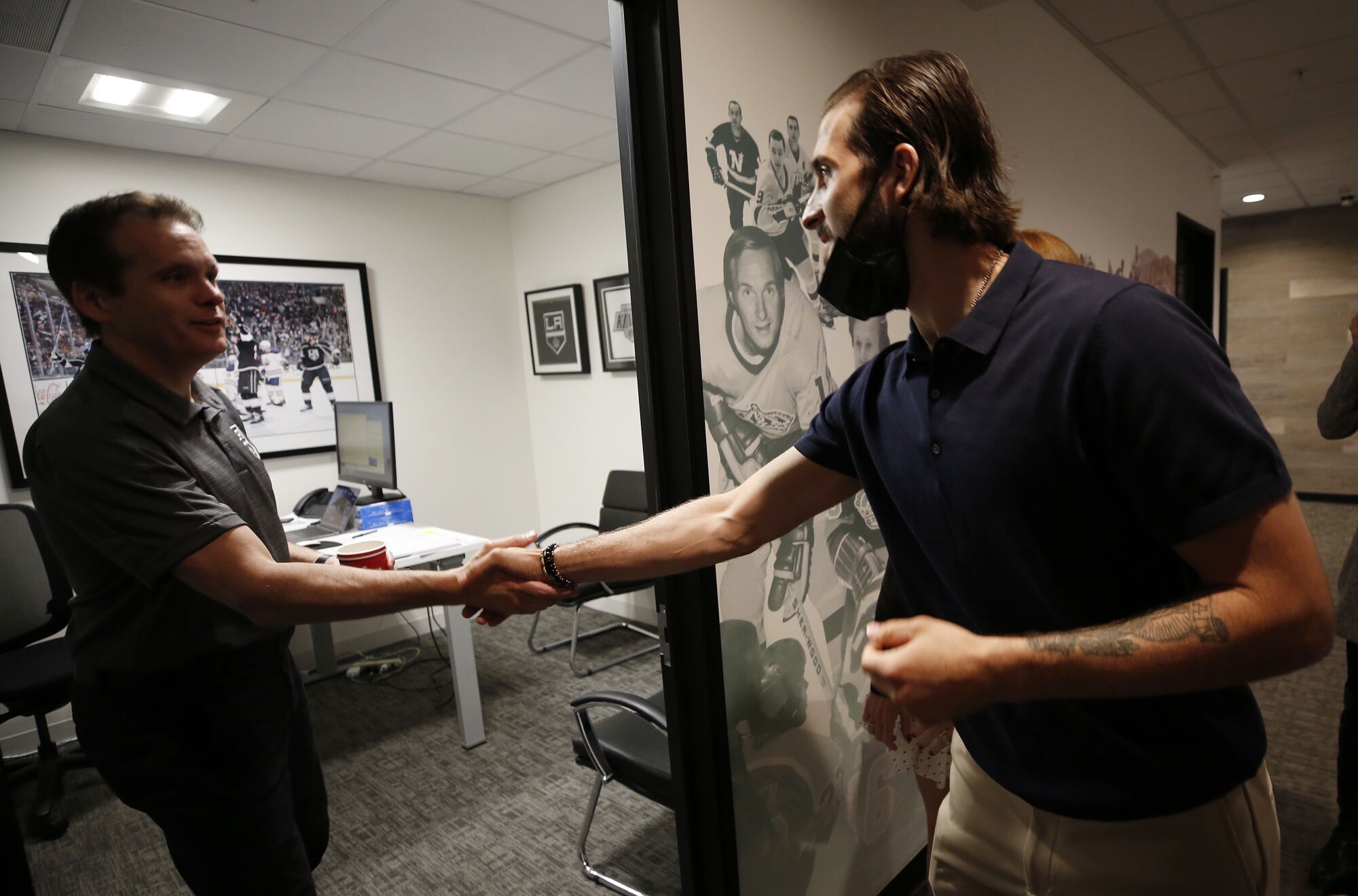 New Kings forward Phillip Danault shakes hands with Rob Koch, director of team operations, at the practice facility.
