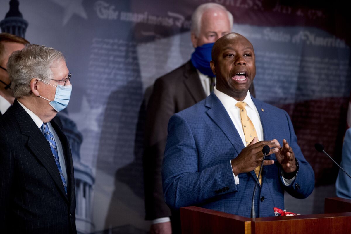 Sen. Tim Scott (R-S.C.), right, speaks as Senate Majority Leader Mitch McConnell, left, and others listen at Capitol Hill.