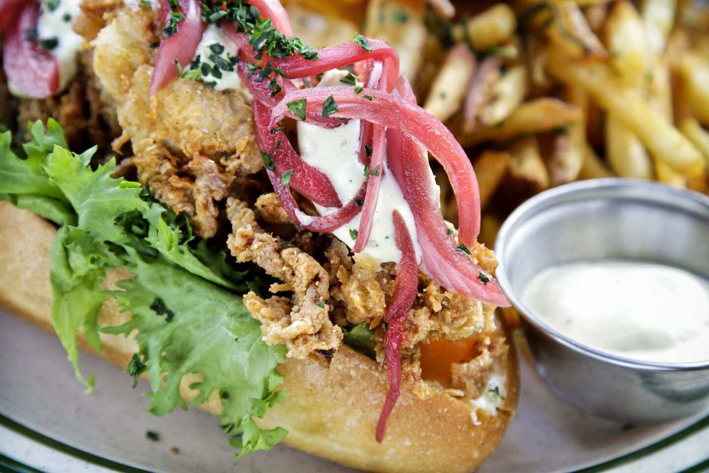 Knife & Fork fried oysters Po'Boy, with sauce gribiche, wild lettuce, tomatoes, pickles, onions and fries.