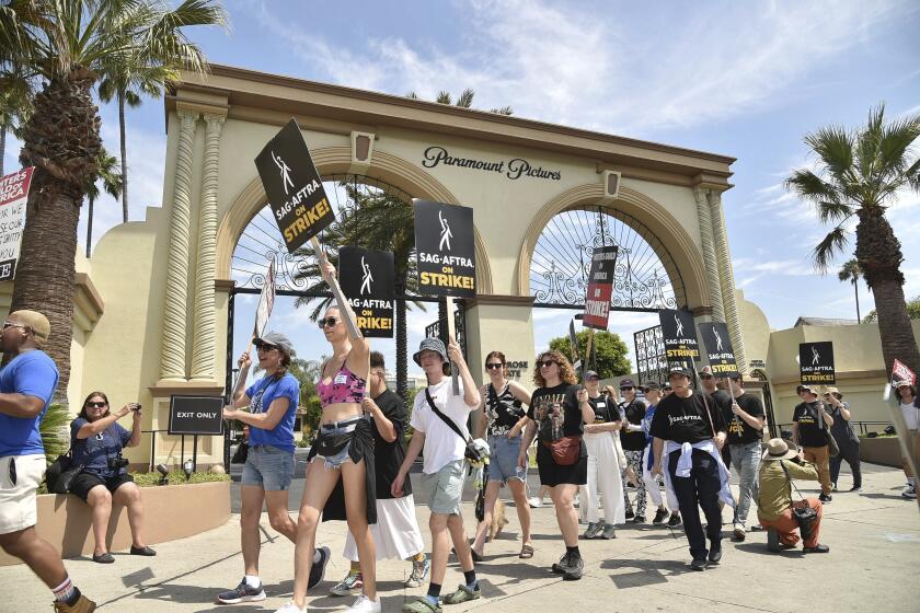 Picketers carry signs outside Paramount studios on Friday, July 21, 2023, in Los Angeles. The actors strike comes more than two months after screenwriters began striking in their bid to get better pay and working conditions. (Photo by Richard Shotwell/Invision/AP)