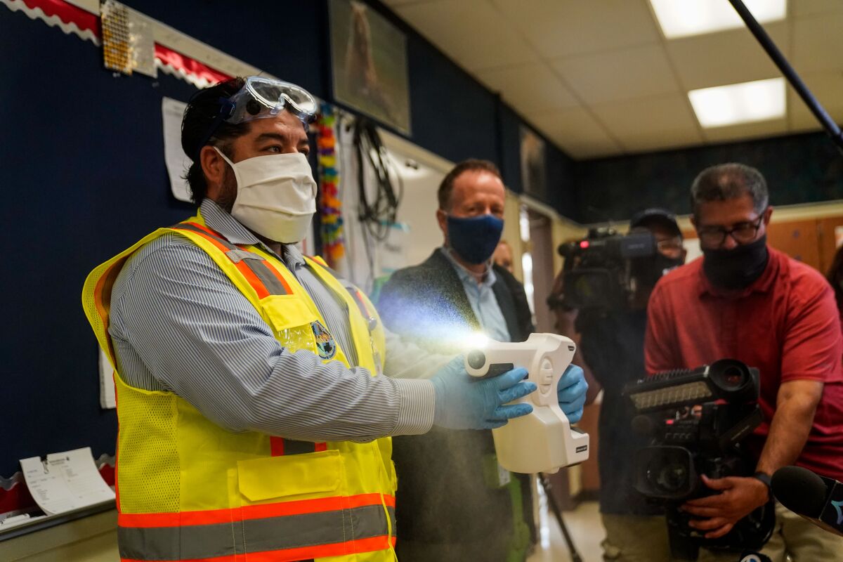 A staff member sprays sanitizer at Burbank Middle School. 