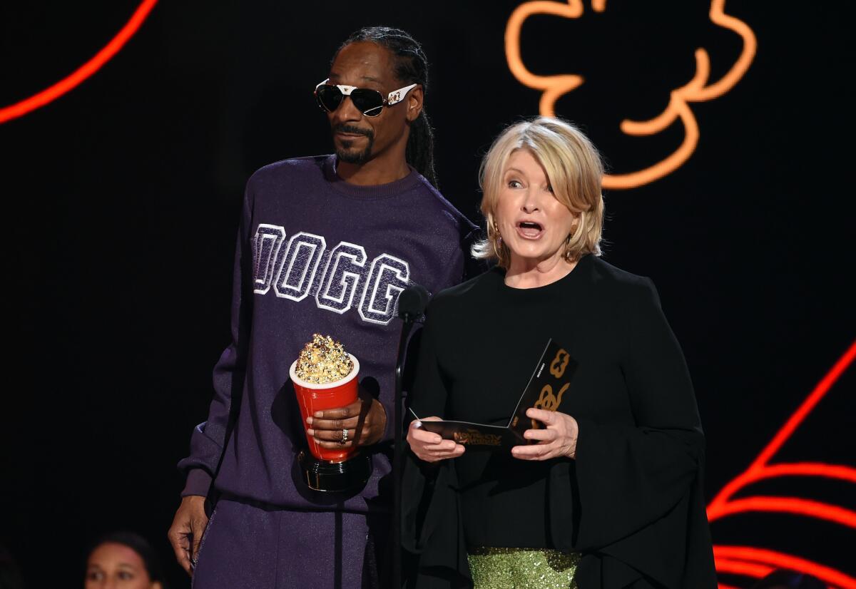 Snoop Dogg holds a popcorn trophy standing next to Martha Stewart.