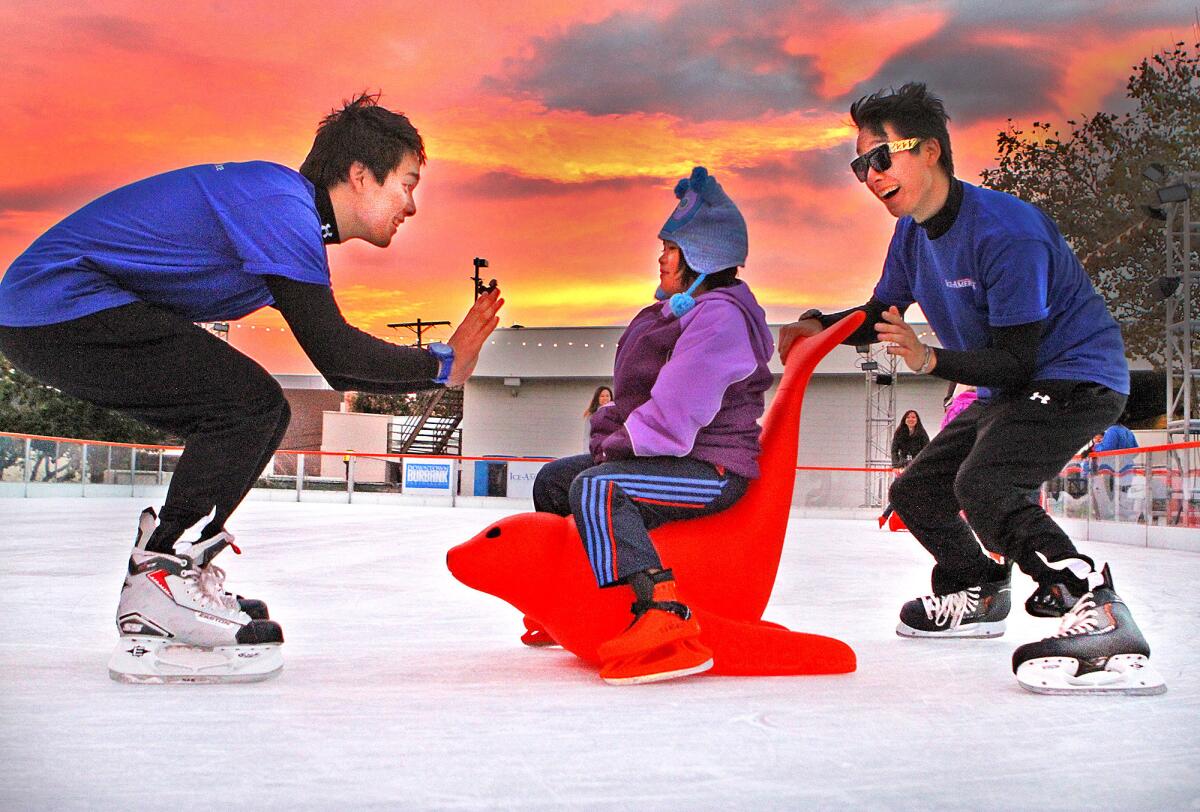 Jeremy Steele and Jourdan Steele, twins, who are skate guards at Ice America, pull Lisa Truong, 7, of North Hills on a red seal on an ice rink behind Burbank City Hall on Friday, Nov. 22, 2013. The rink, which had a grand opening this week, has had about 100 skaters so far, and will remain open through January 5.
