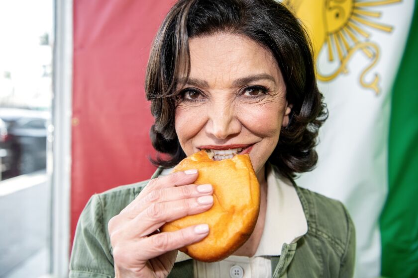 LOS ANGELES, CA - APRIL 14: Shohreh Aghdashloo bites into a cream-filled piroshki from Jordan market on Friday, April 14, 2023 in Los Angeles, CA. (Mariah Tauger / Los Angeles Times)