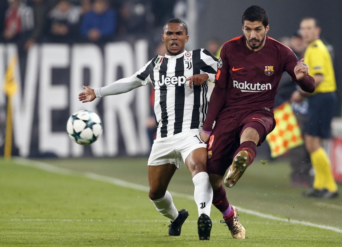 El uruguayo Luis Suárez, del Barcelona, envía un pase junto al brasileño Douglas Costa, de la Juventus, en un encuentro de la Liga de Campeones de Europa disputado el miércoles 22 de noviembre de 2017 en Turín, Italia