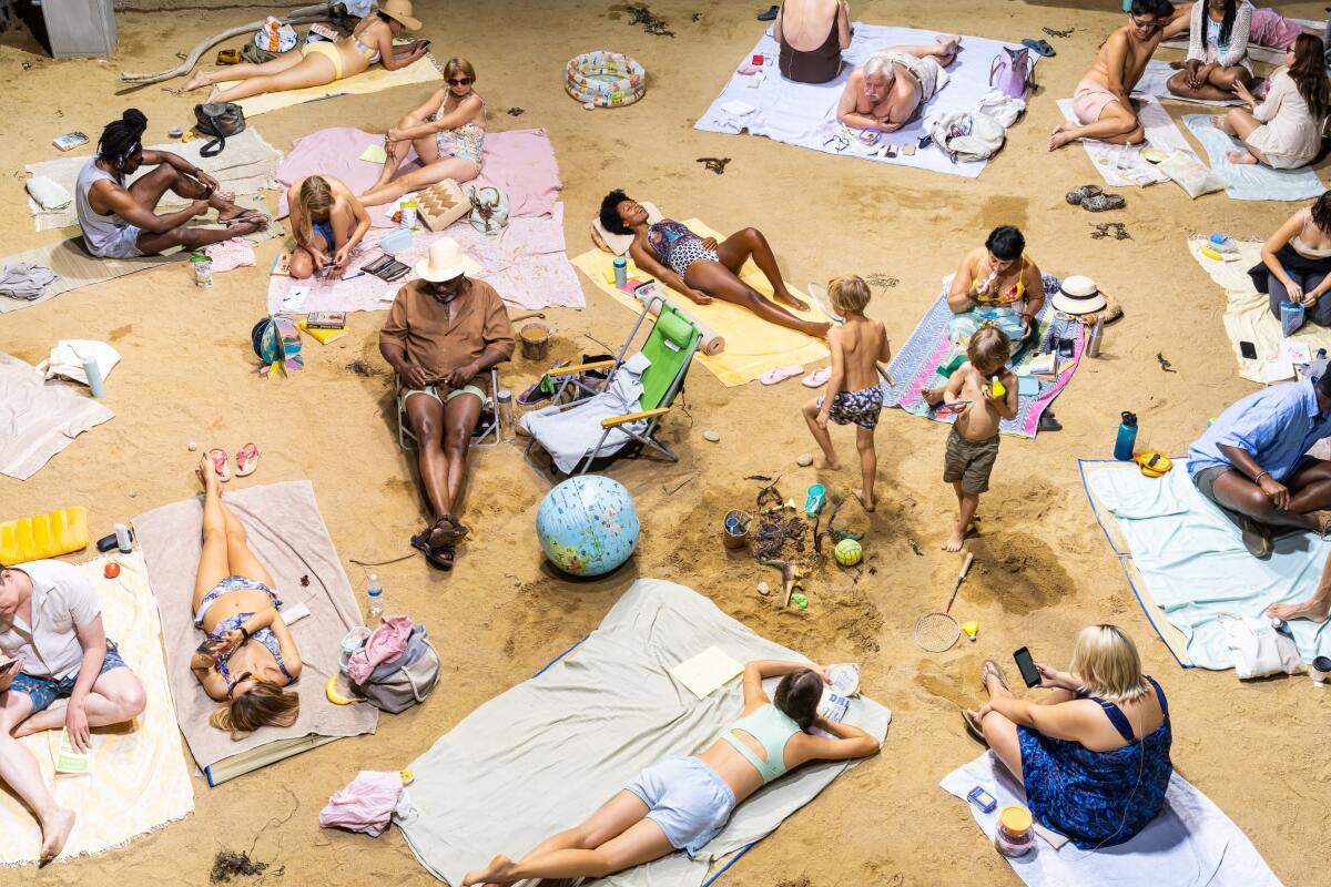 Performers playing beachgoers lounge and sing on the sand.