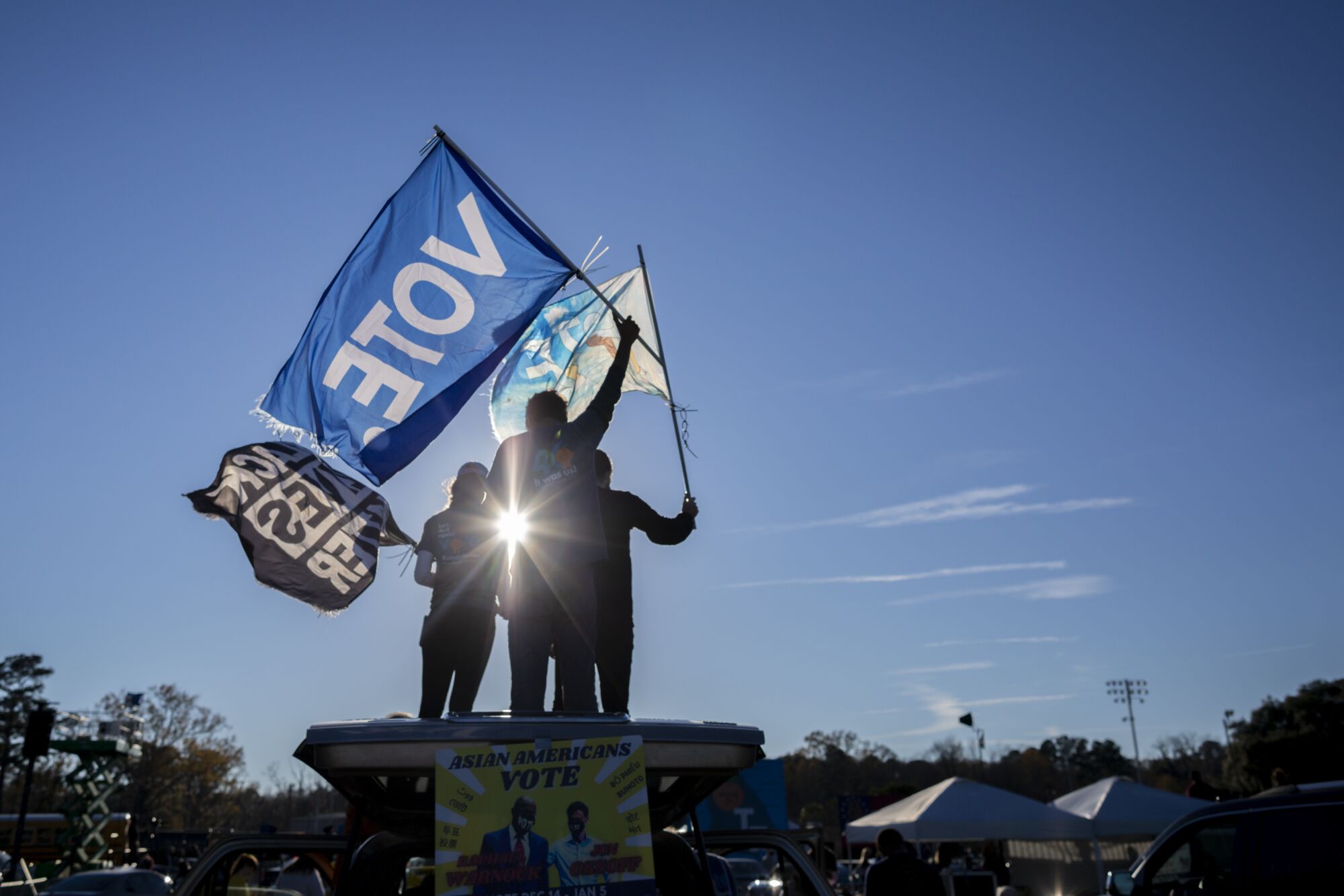Supporters wave flags as they wait for Vice President-elect Kamala Harris at a drive-in rally