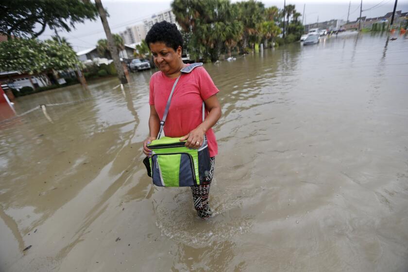 Esther Martens walk through a flooded roadway to get to her car in the West End section of New Orleans.