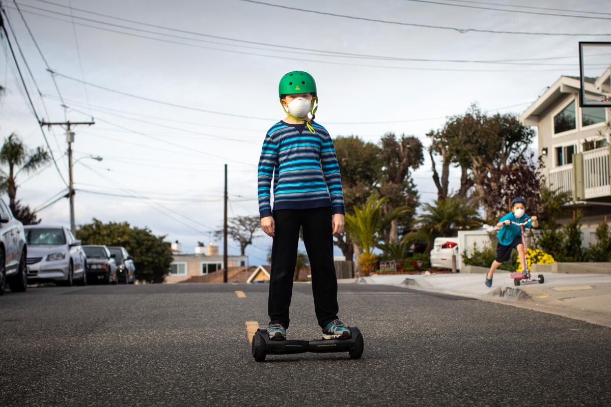 Children wearing face masks play in the streets of Redondo Beach during the coronavirus pandemic.