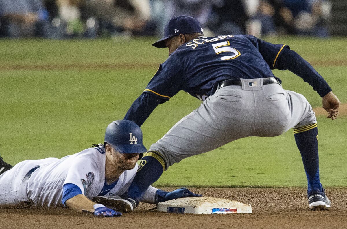 Dodgers' Brian Dozier steals second base on a late throw to Milwaukee Brewers second baseman Jonathan Schoop in the third inning on Tuesday.