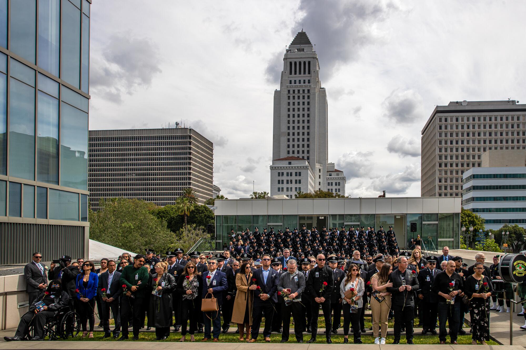 Police officers, families and friends of fallen officers assemble near LAPD headquarters. City Hall is behind. 