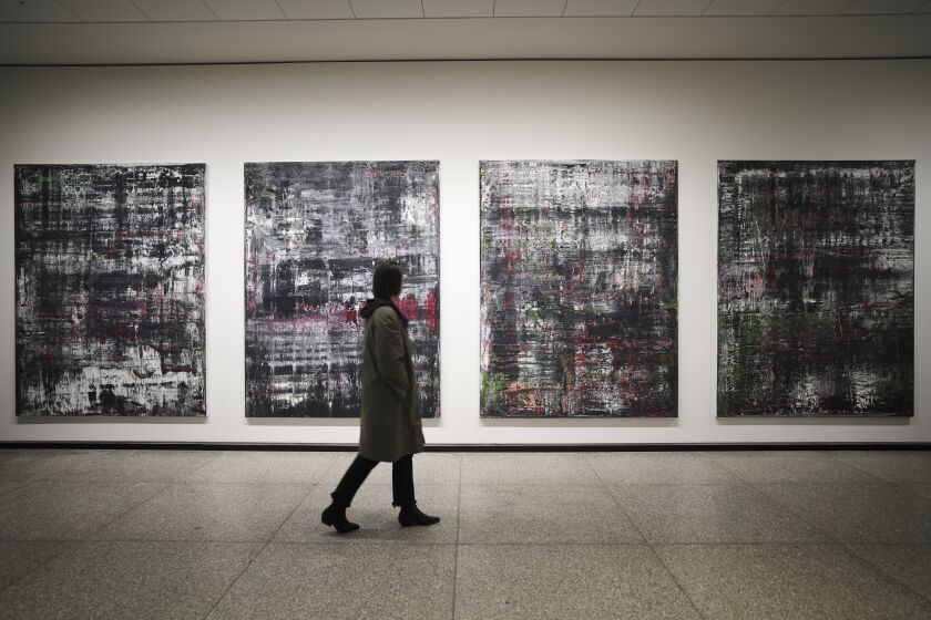 A woman walks in front of the 'Birkenau' paintings in a new exhibition with art works of German artist Gerhard Richter at the New National Gallery in Berlin, Germany, Friday, March 31, 2023. Richter's foundation gave on permanent loan 100 works of the artist to the New National Gallery where they will be shown in the permanent exhibition. (AP Photo/Markus Schreiber)
