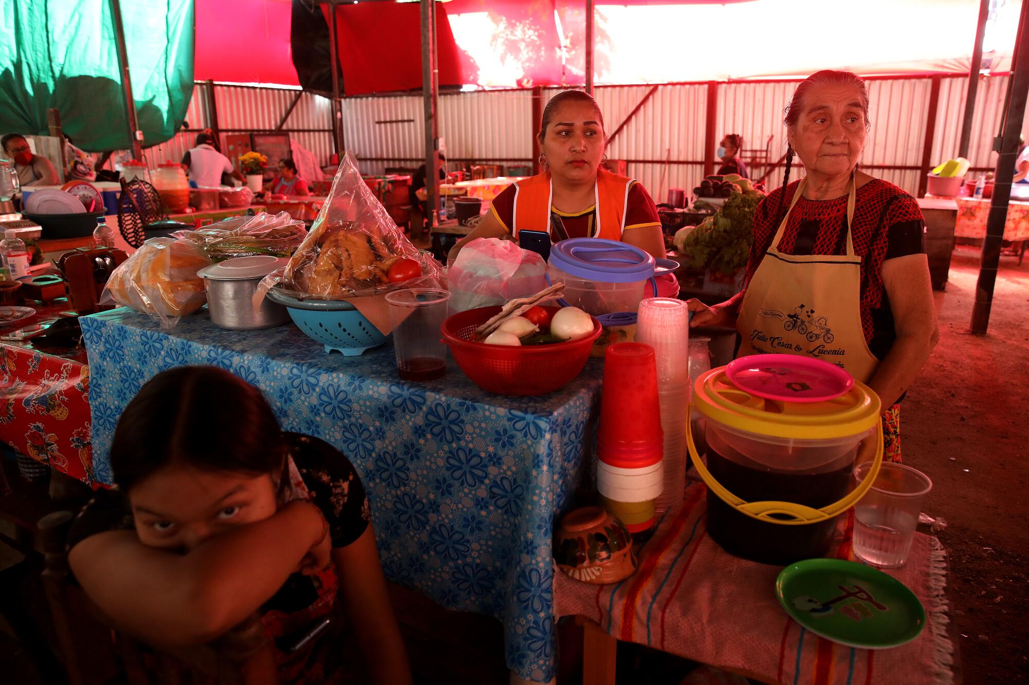 A teenager and two women at a food stall.