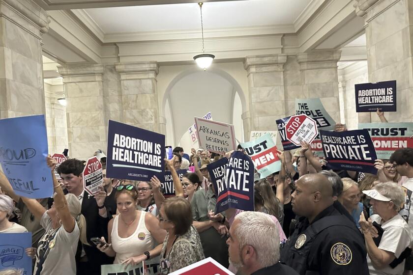 Supporters and opponents of a proposed ballot measure to scale back Arkansas' abortion ban hold signs outside the old Supreme Court chamber at the state Capitol in Little Rock, Ark. Friday, July 5, 2024. Organizers submitted petitions to try and get the proposals on the November ballot. (AP Photo/Andrew DeMillo)