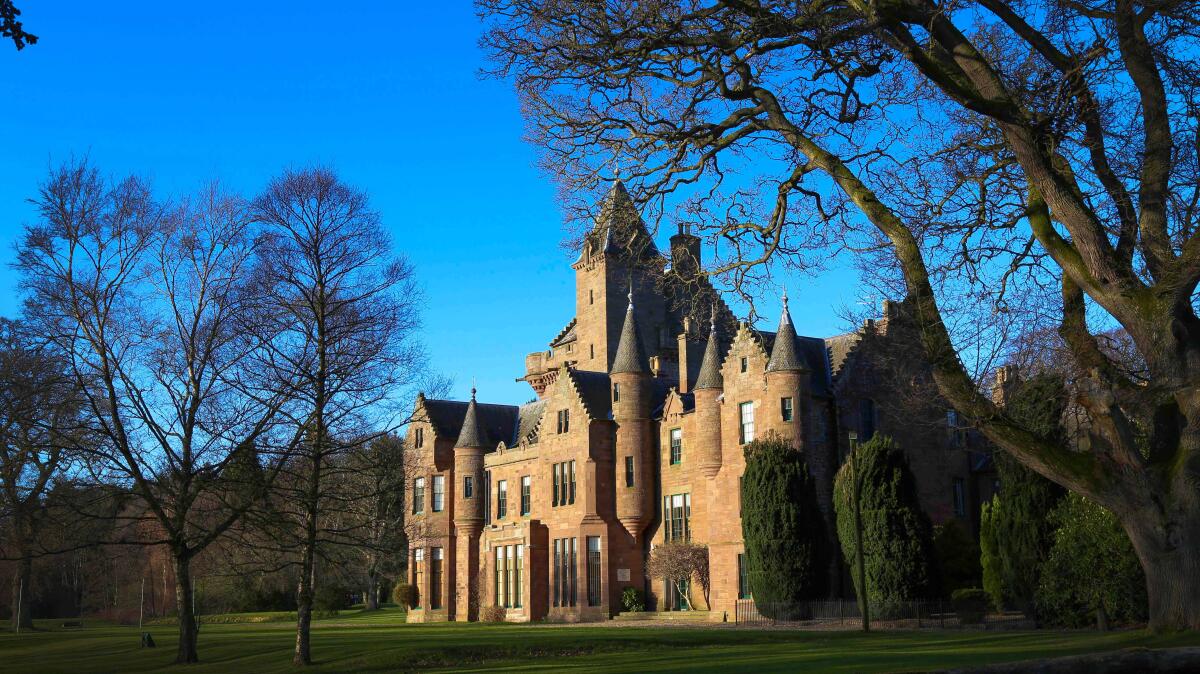 A brick castle surrounded by trees and lawn.