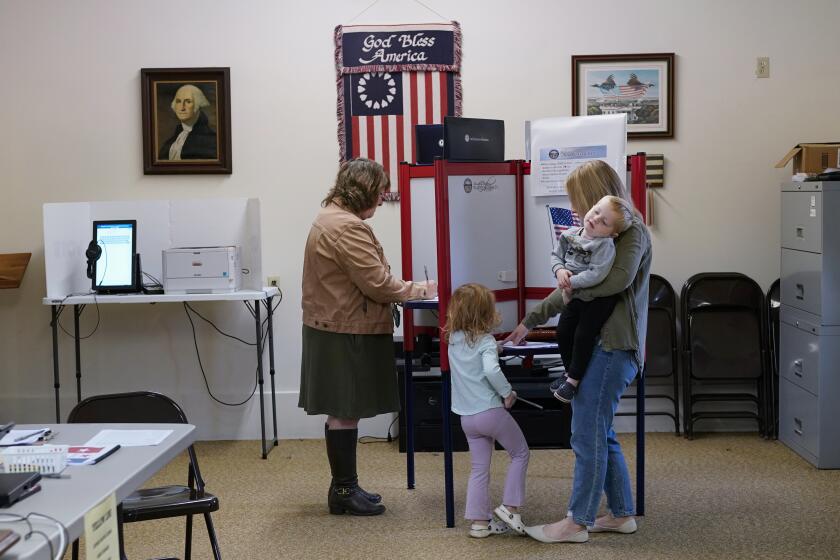 Lauren Miracle, right, holds her son Dawson, 1, as she helps her daughter Oaklynn, 3, fill out a child's practice ballot before voting herself at a polling location in the Washington Township House in Oregonia, Ohio, Tuesday, Nov. 7. Polls are open in a few states for off-year elections that could give hints of voter sentiment ahead of next year's critical presidential contest. (AP Photo/Carolyn Kaster)