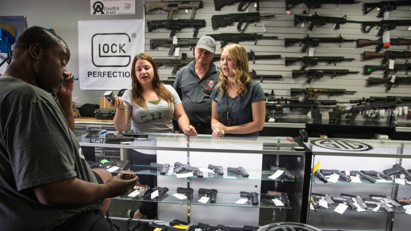 Store managers Jamie Taflinger, left, and Kendyll Murray show customer Cornell Hall of Highland different types of ammo at the Get Loaded gun store in Grand Terrace, Calif. Voters in the state will decide in November whether purchasing ammo should require a background check.