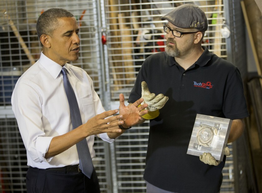 President Obama meets Terry Sandin, who is holding a replica of the presidential seal he made, during a tour of TechShop, a fabrication and prototyping studio in Pittsburgh.