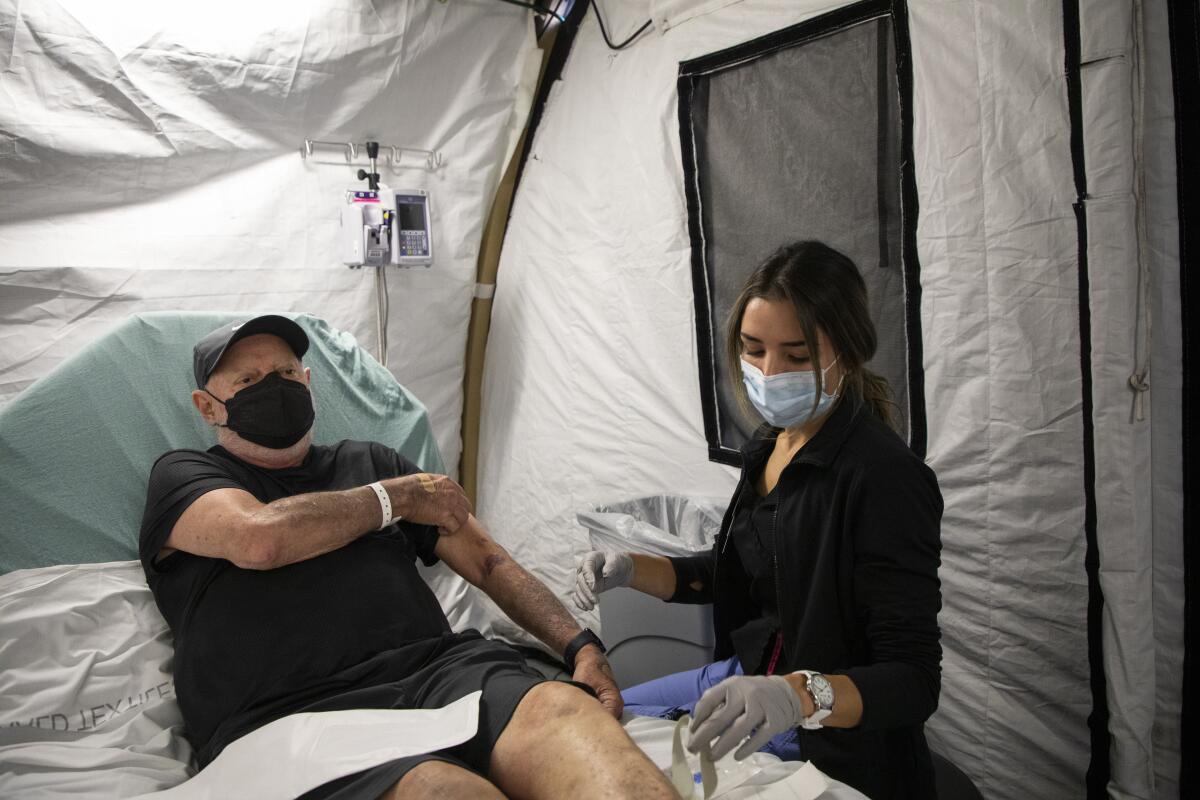 Registered nurse Jessica Smith draws the blood of Mark Swenson in an overflow tent at Scripps Memorial Hospital Encinitas
